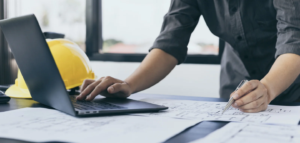 Man op laptop aan het werk om kalkzandsteenwanden uit te tekenen.