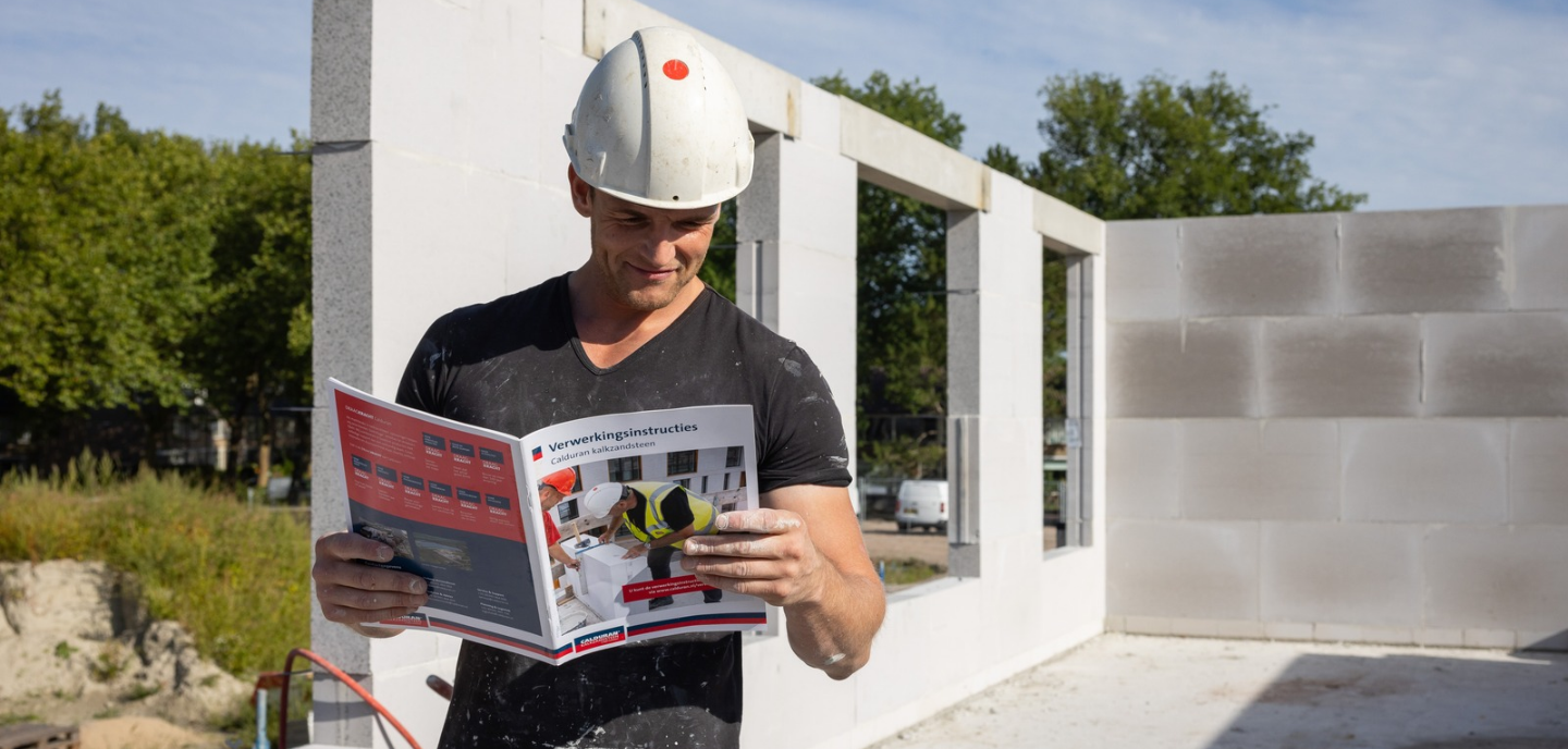Verwerker, man, leest verwerkingsinstructies voor wandopbouw kalkzandsteen.