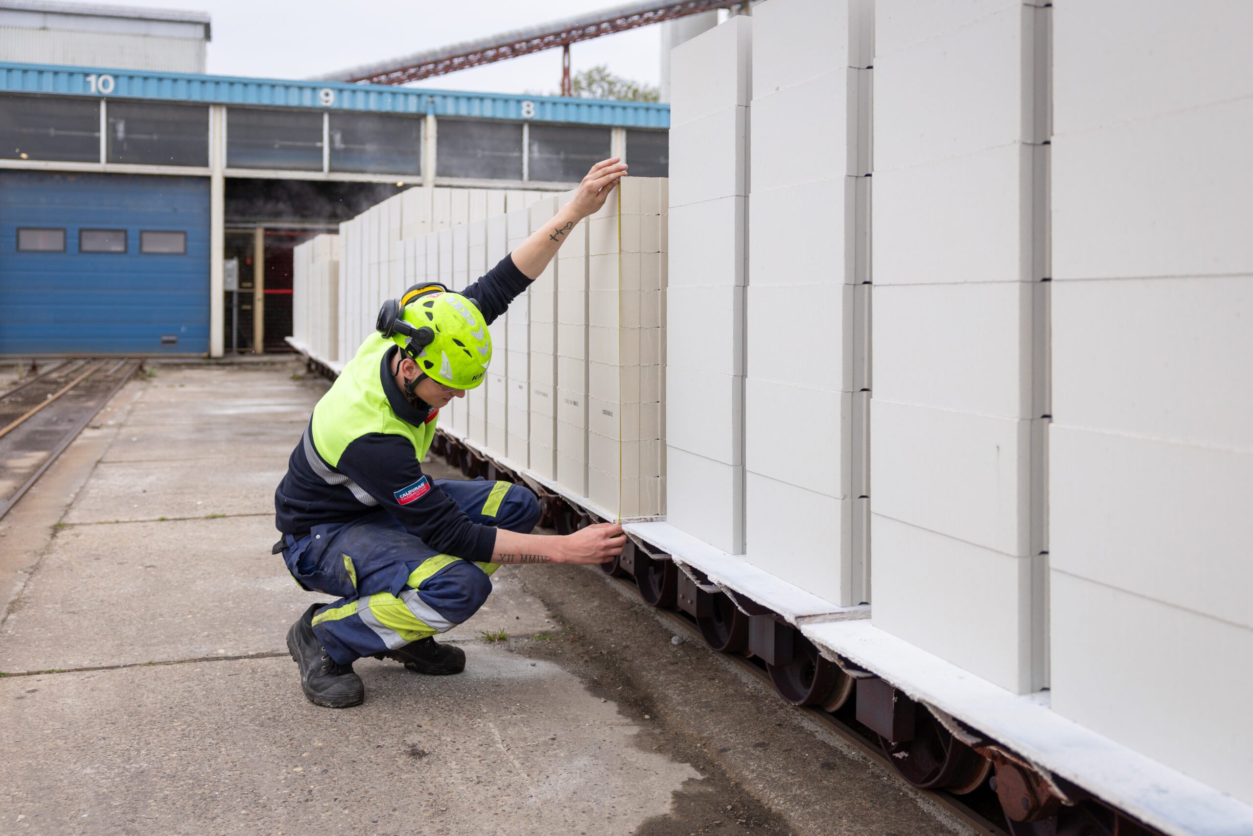 Medewerker, man, kalkzandsteenproducten aan het meten met meetlint.