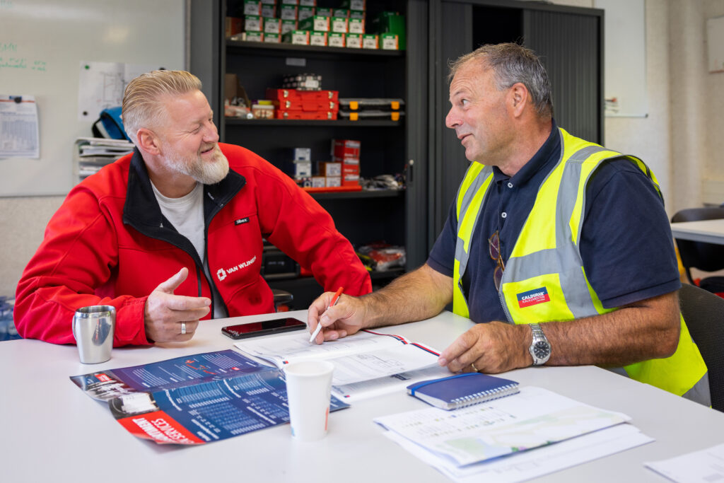 Medewerker Calduran, man, in gesprek met de aannemer, man, in bouwkeet.