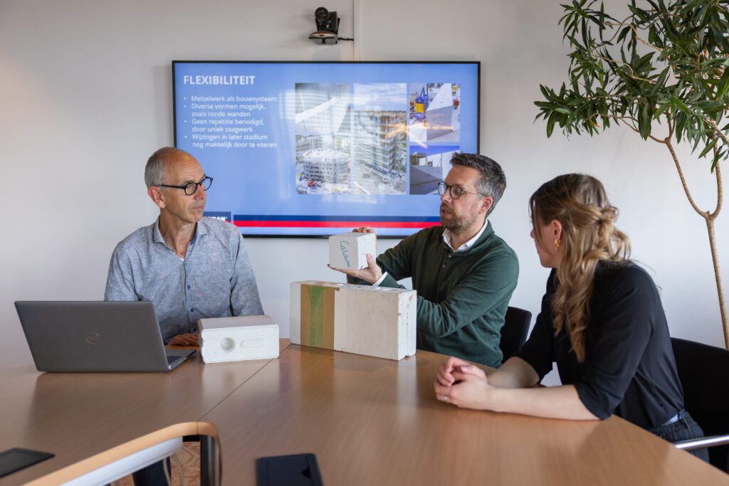 Medewerker Techniek en Advies legt uit over kalkzandsteen in een vergaderzaal aan twee andere collega's.